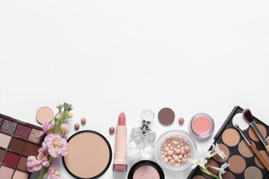Flat lay composition with different makeup products and beautiful flowers on white background, space for text