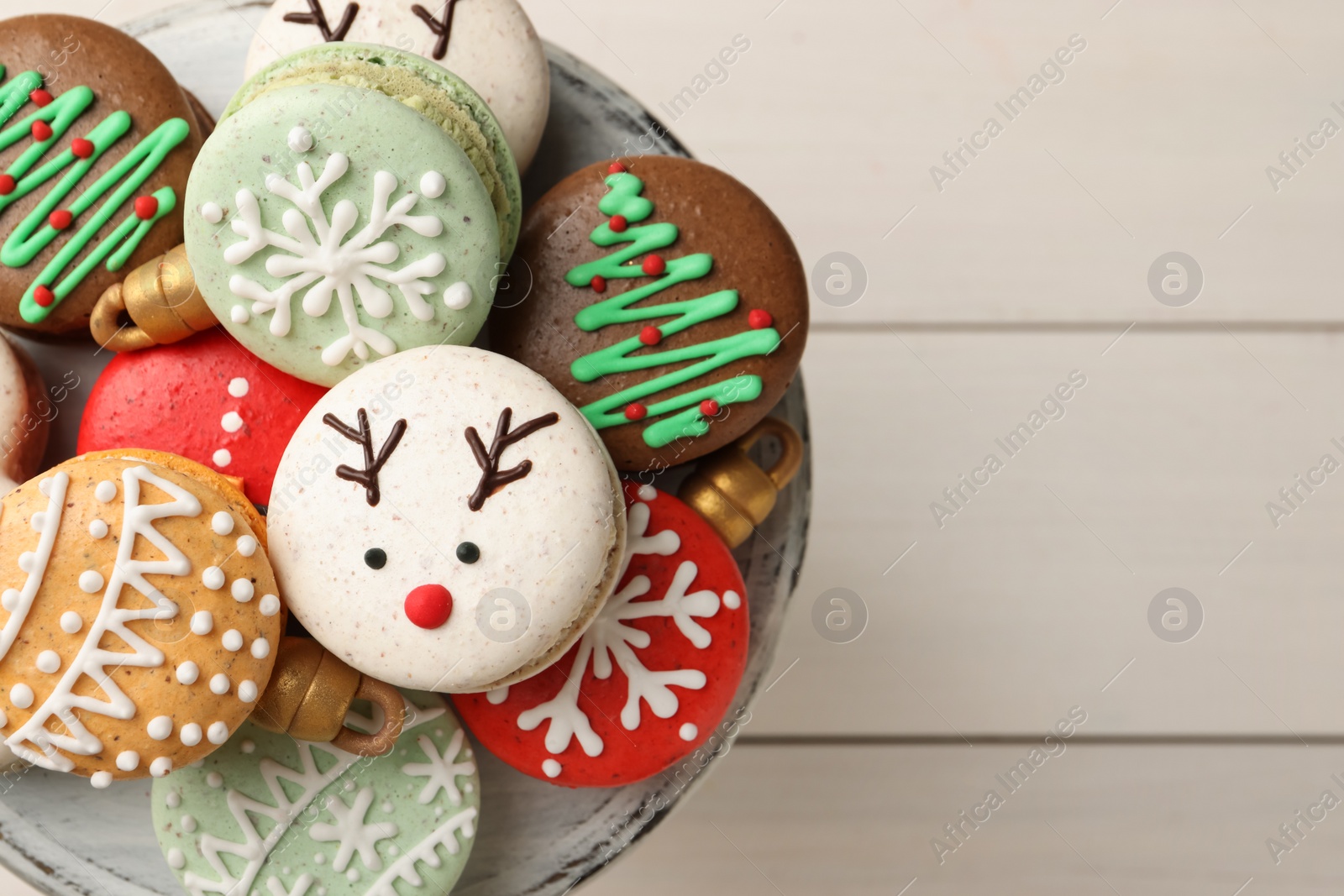 Photo of Beautifully decorated Christmas macarons on white wooden table, top view. Space for text