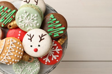 Photo of Beautifully decorated Christmas macarons on white wooden table, top view. Space for text
