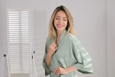 Photo of Pretty young woman in beautiful silk robe at home