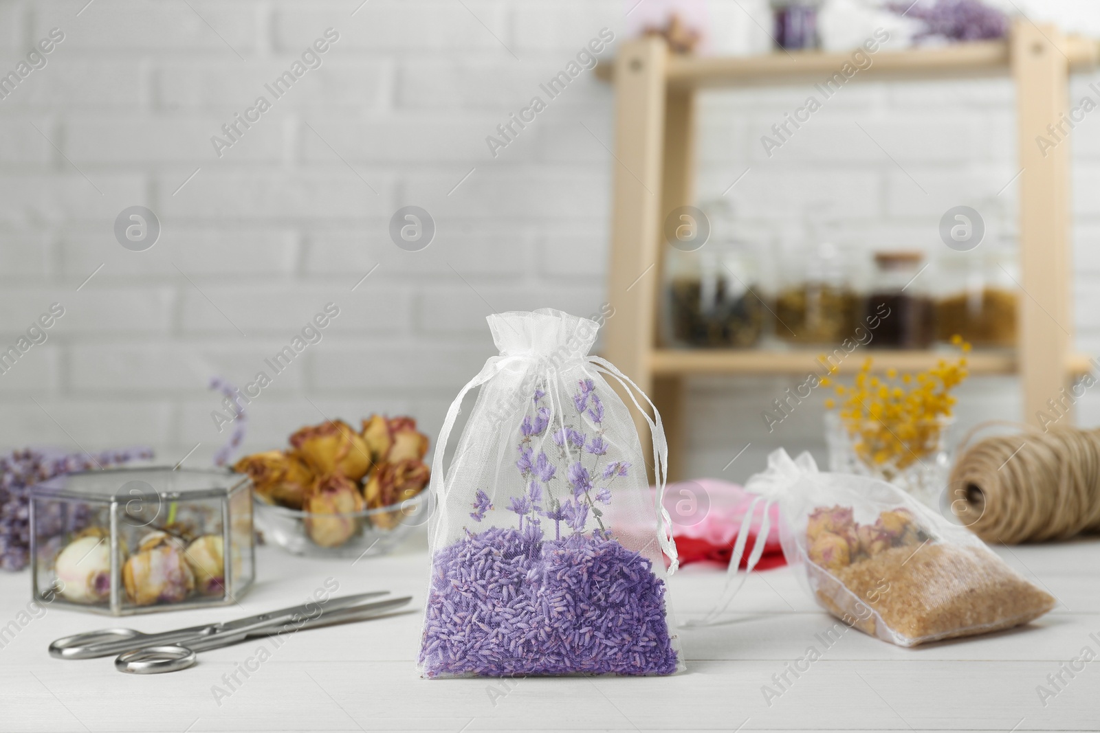 Photo of Scented sachet with dried lavender flowers on white table