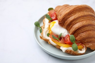 Tasty croissant with fried egg, tomato and microgreens on white background, closeup. Space for text