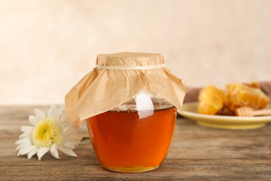 Photo of Jar with sweet honey on table against color background
