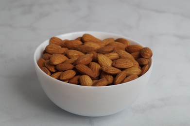 Bowl of delicious almonds on white marble table