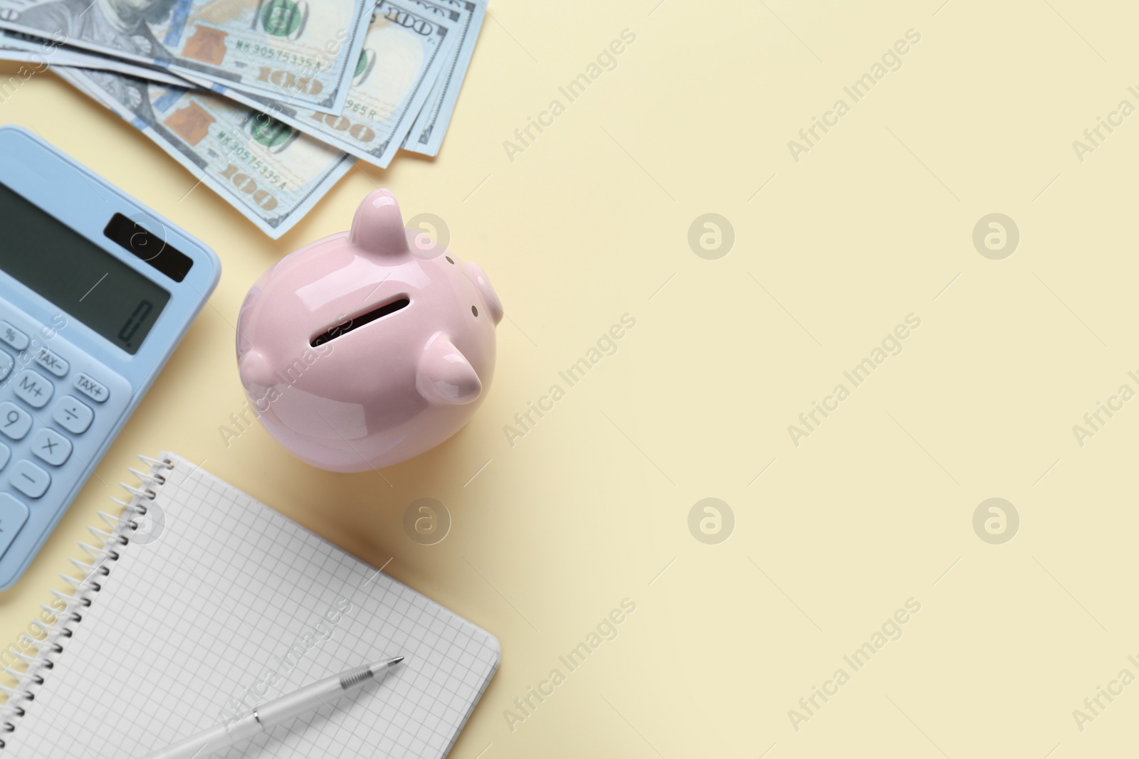 Photo of Piggy bank, banknotes and calculator on beige background, flat lay. Space for text