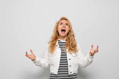 Photo of Aggressive young woman screaming with rage on white background