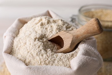 Photo of Sack with quinoa flour and wooden scoop, closeup view