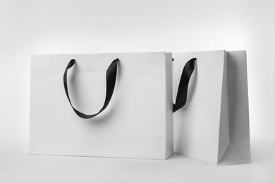 Photo of Paper shopping bags with ribbon handles on white background. Mockup for design