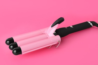 Photo of Modern triple curling iron on pink background