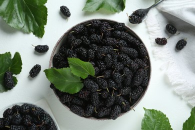 Bowl of delicious ripe black mulberries on white table, flat lay