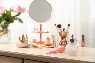 Dressing table with different makeup products and accessories in room interior