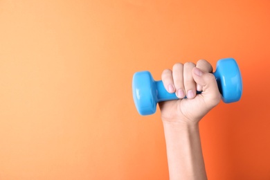 Photo of Woman holding vinyl dumbbell on color background, closeup with space for text