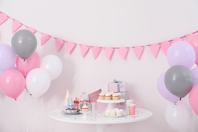 Party treats and items on table in room decorated with balloons