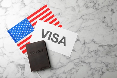 Photo of Flat lay composition with flag of USA, passport and word VISA on marble background. Space for text