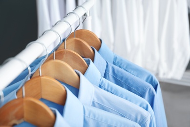 Rack with clean clothes on hangers after dry-cleaning indoors