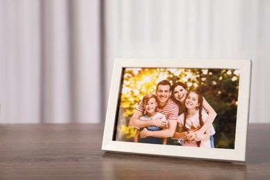 Photo of Frame with family photo on wooden table indoors, space for text