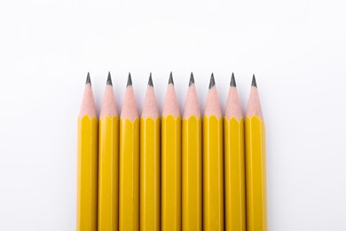 Many sharp graphite pencils on white background, top view