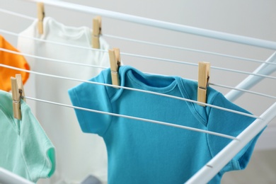 Photo of Different cute baby onesies hanging on clothes line. Laundry day