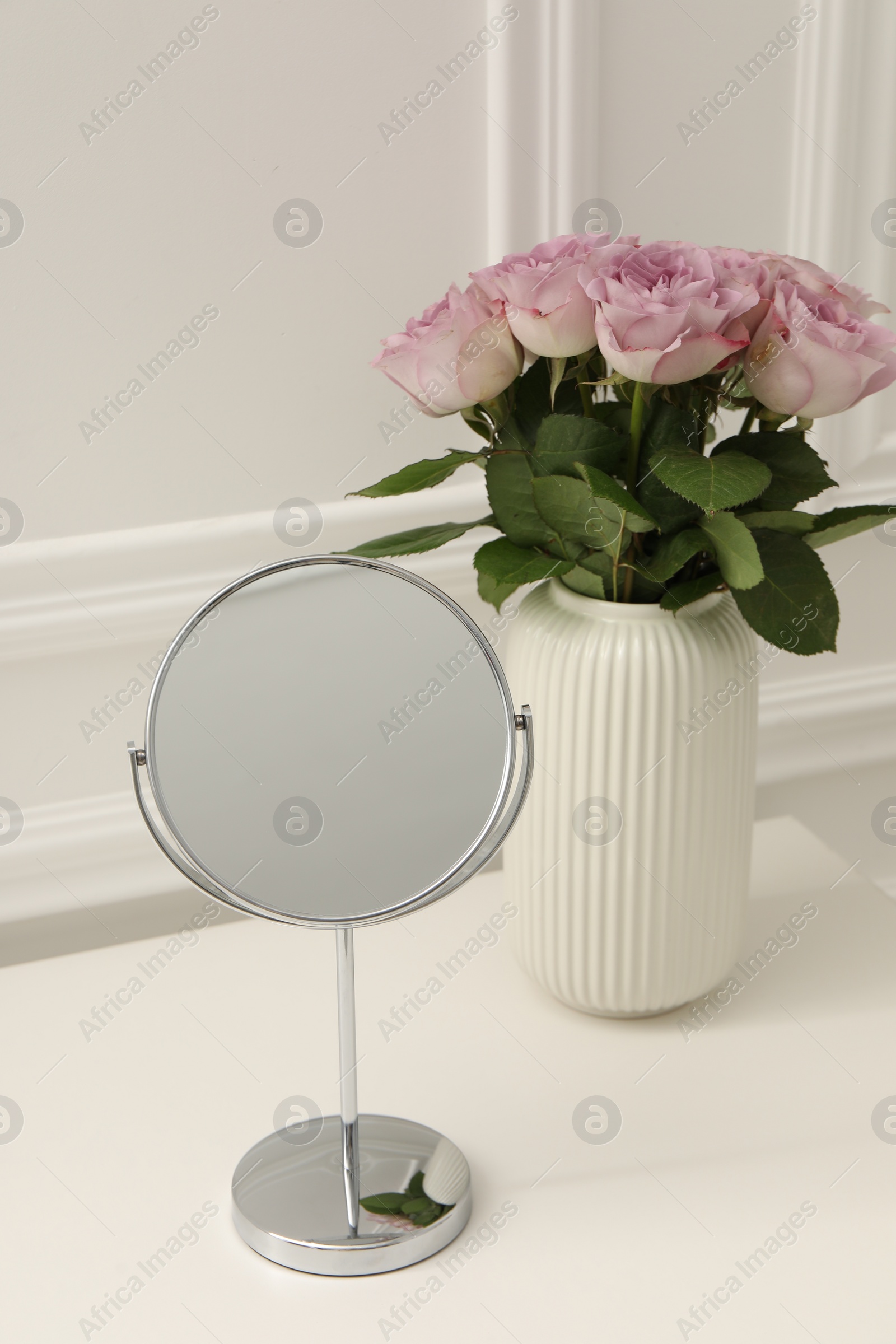 Photo of Mirror and vase with pink roses on white dressing table