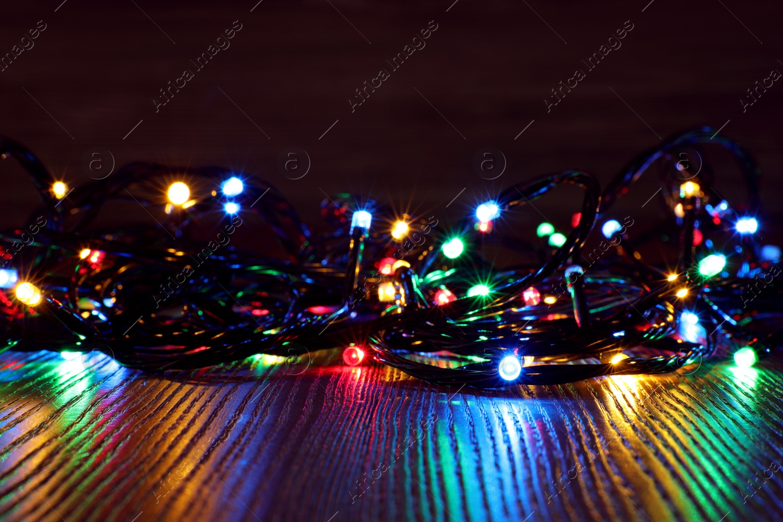 Photo of Beautiful colorful Christmas lights on wooden table