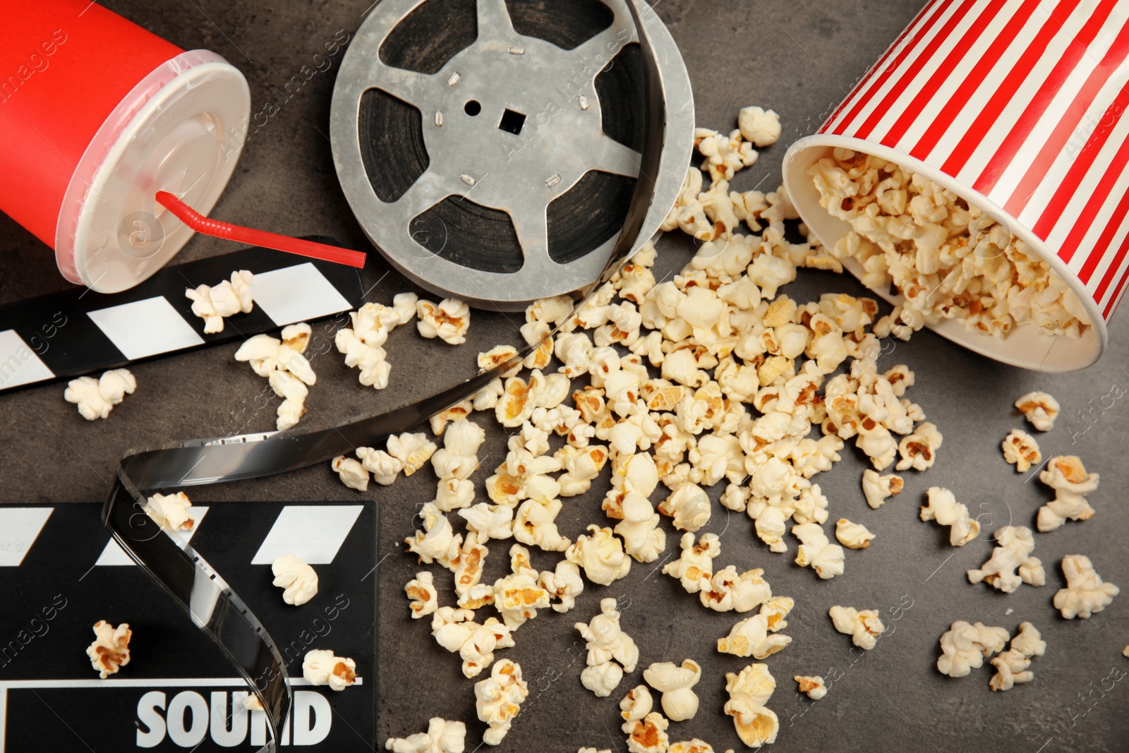 Photo of Flat lay composition with popcorn, film reel and clapperboard on grey background