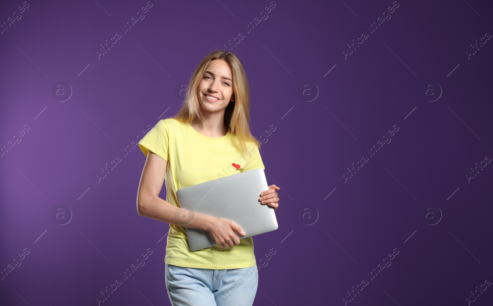 Photo of Portrait of young woman with modern laptop on purple background