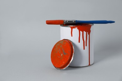 Photo of Can of orange paint and brush on grey background. Space for text