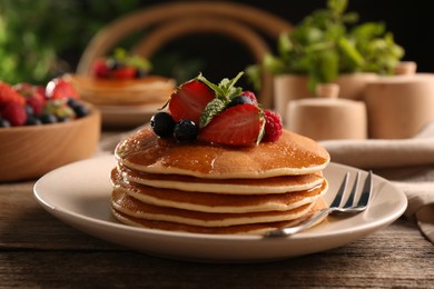 Photo of Tasty pancakes with fresh berries and mint on wooden table, closeup