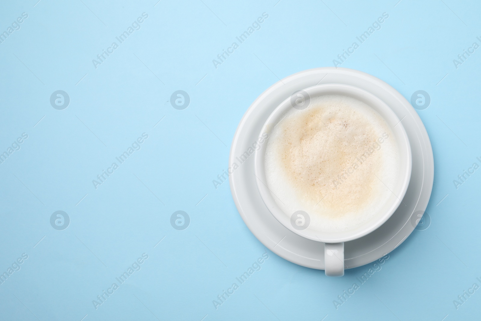 Photo of Aromatic coffee in cup on light blue background, top view. Space for text