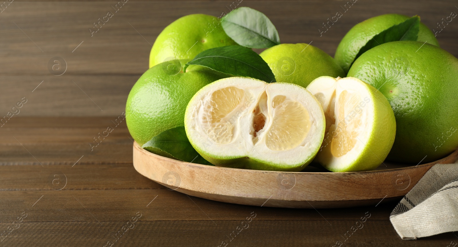 Photo of Whole and cut sweetie fruits on wooden table