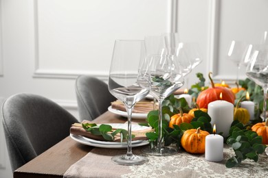 Photo of Beautiful autumn table setting. Plates, cutlery, glasses, pumpkins and floral decor