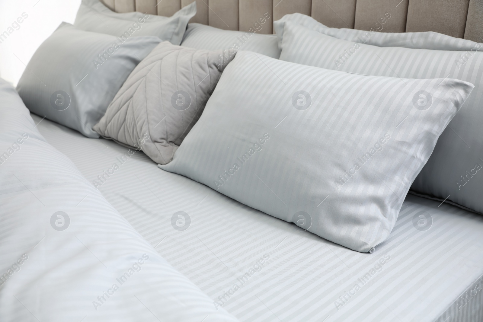 Photo of Many soft pillows and blanket on large comfortable bed