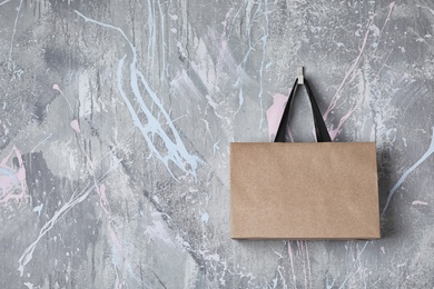 Paper shopping bag with handles hanging on color wall. Mock up for design