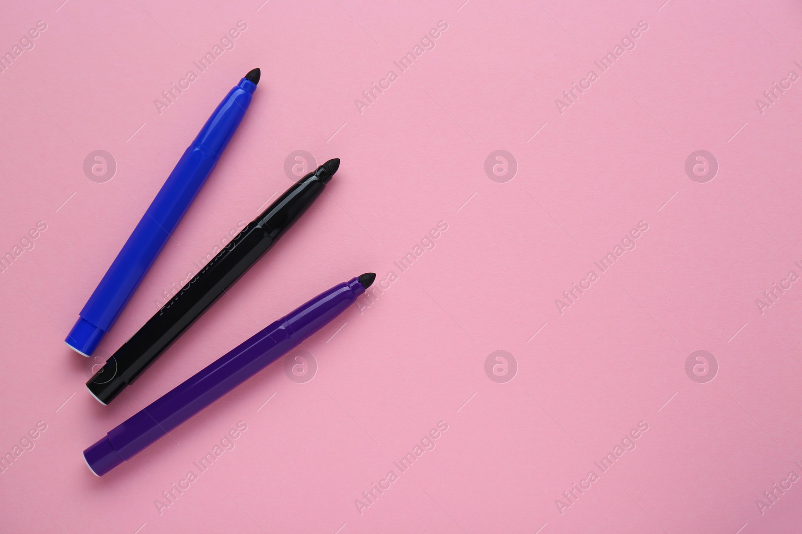 Photo of Different colorful markers on light pink background, flat lay. Space for text