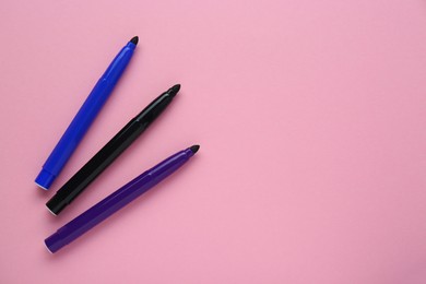 Photo of Different colorful markers on light pink background, flat lay. Space for text