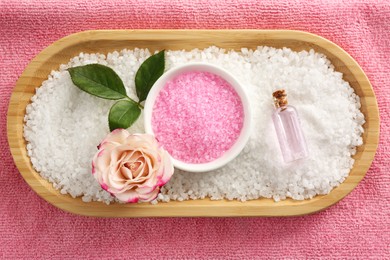 Aromatic sea salt and beautiful flower on pink towel, flat lay