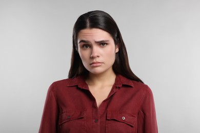 Sadness. Unhappy woman in red shirt on gray background