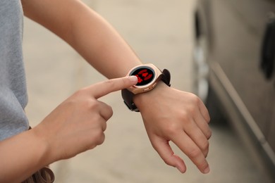 Woman using SOS function on smartwatch outdoors, closeup