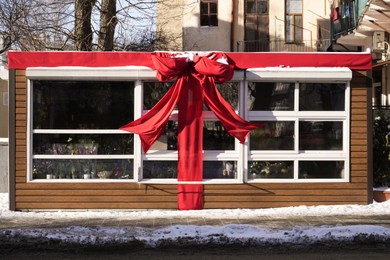Photo of Beautiful flower shop decorated with red bow outdoors