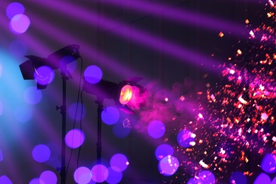 Image of Bright spotlights, beams of light and falling shiny confetti in night club, bokeh effect