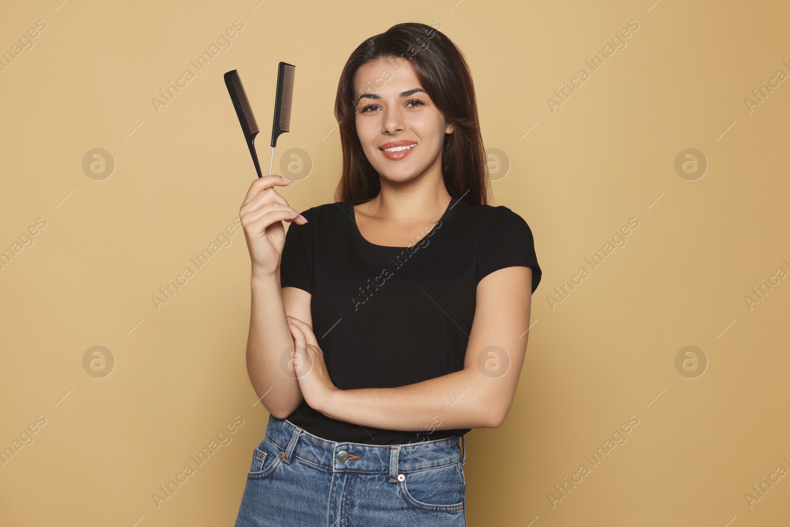 Photo of Happy professional hairdresser with combs against pale orange background