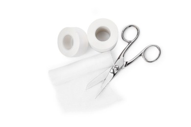 Photo of Medical bandage rolls, sticking plaster and scissors on white background, top view