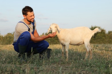 Photo of Man feeding goat at farm. Animal husbandry