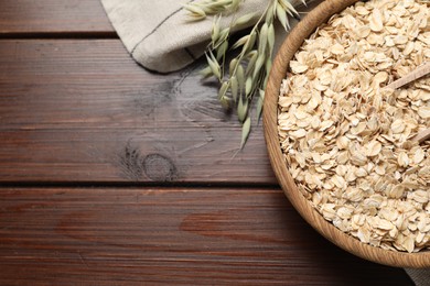 Oatmeal and branches with florets on wooden table, flat lay. Space for text