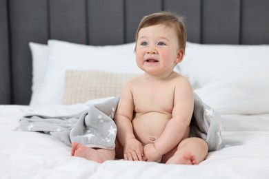 Cute baby boy sitting on bed at home