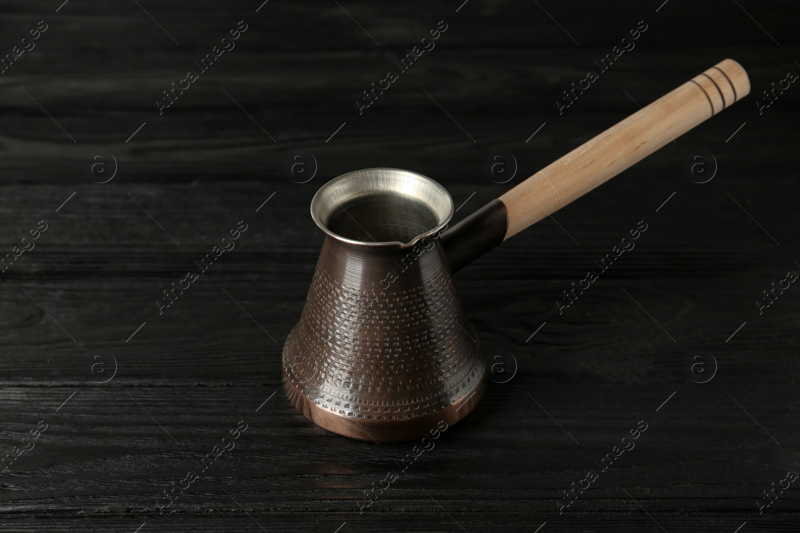 Photo of Copper turkish coffee pot on black wooden table