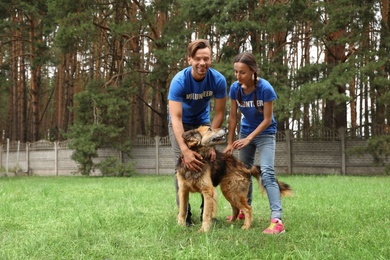 Volunteers with homeless dog at animal shelter outdoors