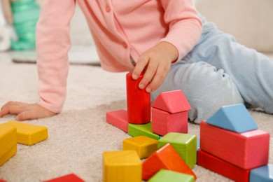 Cute little girl playing with colorful building blocks indoors, closeup