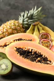 Photo of Fresh ripe papaya and other fruits on grey table, closeup