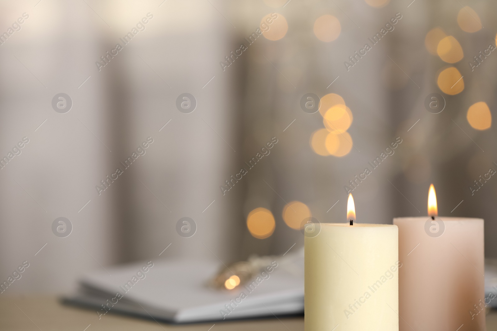 Photo of Burning candles against blurred lights, closeup. Space for text